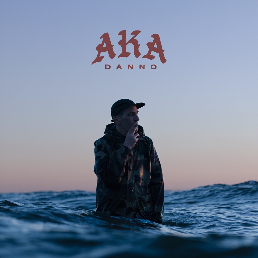 Copertina di A.K.A Danno: Danno immerso nell’acqua al tramonto